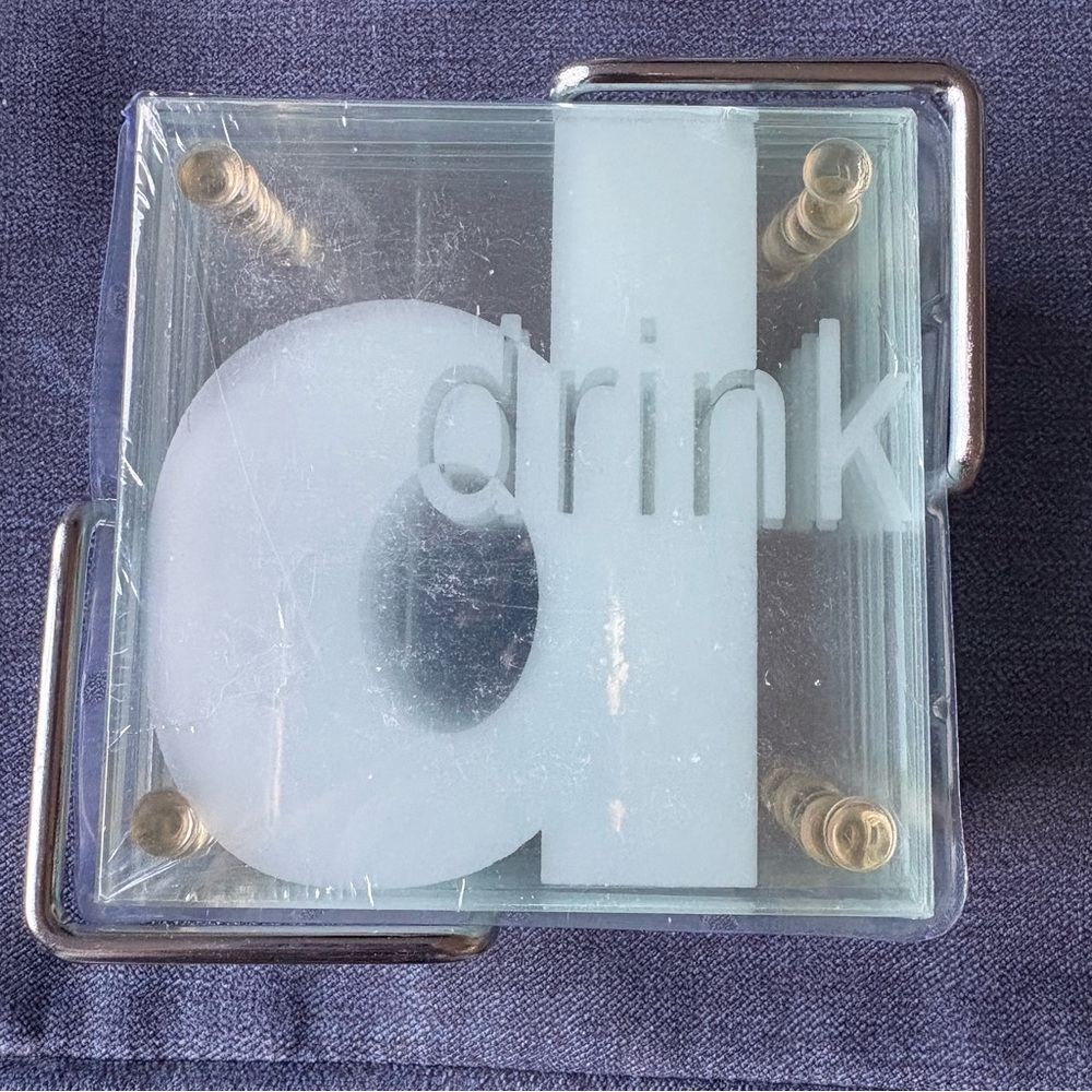Casamoda Tempered Glass Coaster Set with Chrome Caddy. Etched image says drink.